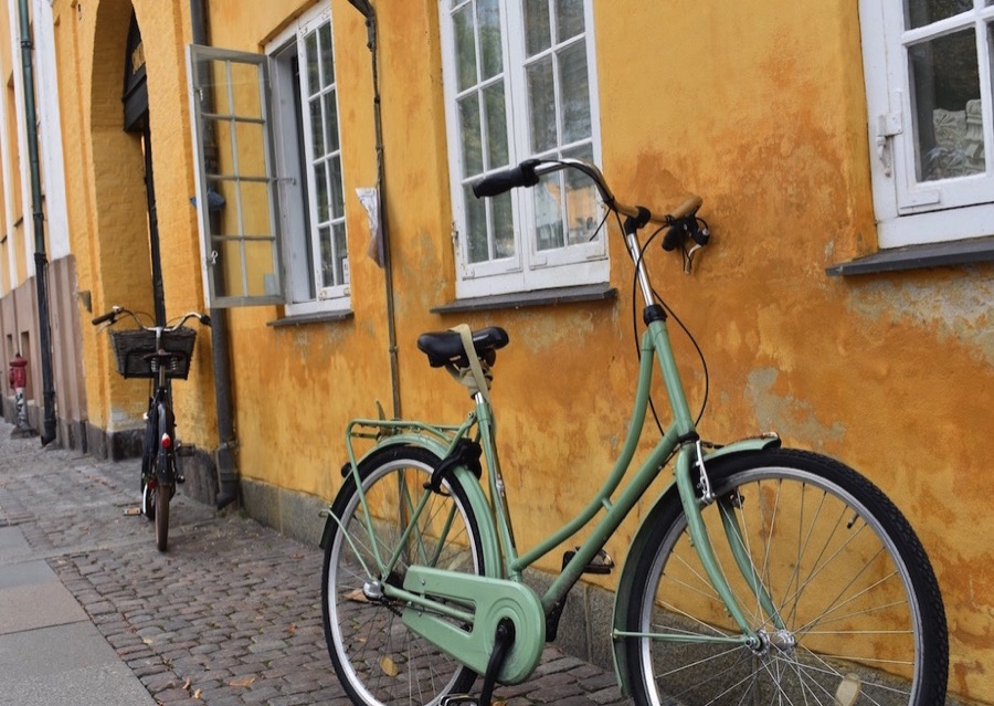 Green bicycle leaning against a yellow wall